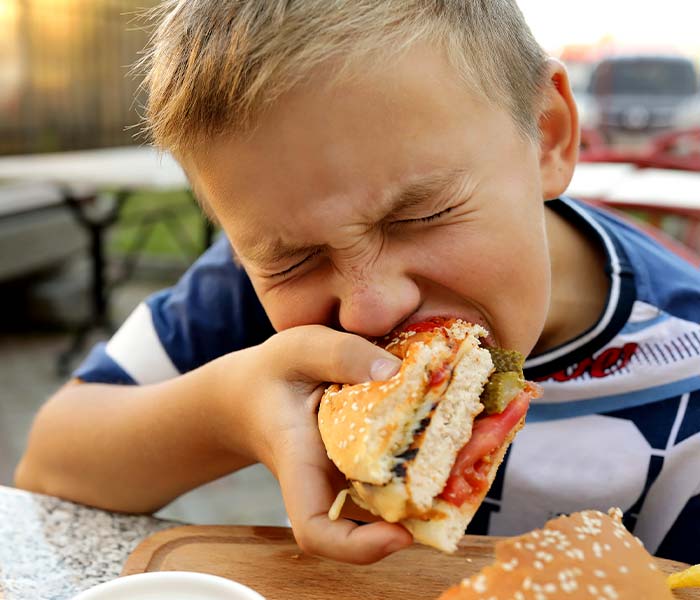 A kid takes a big bite out of a chicken sandwich at Oceans restaurant in Panama City Beach Florida, a family friendly restaurant